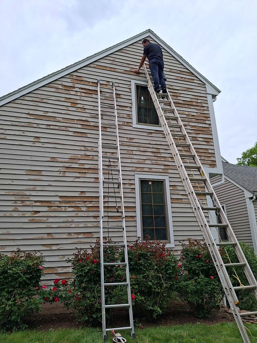 A DDP crew painting, spraying and power washing a two-storey home exterior